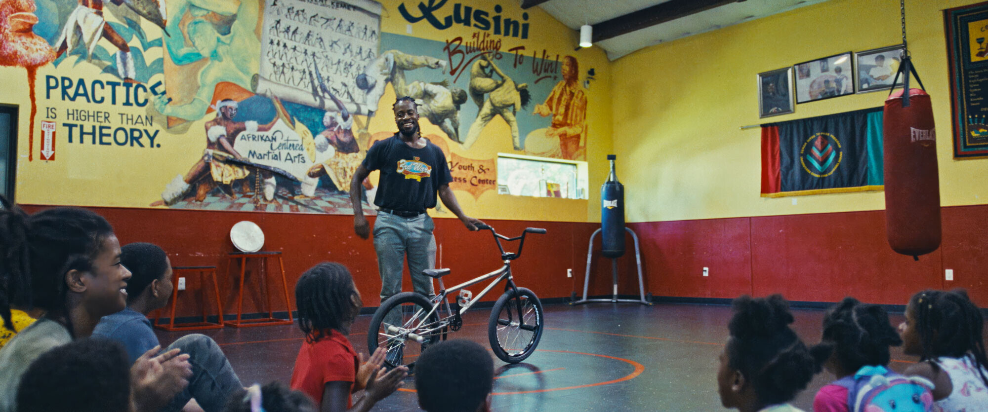 Omari Cato presenting BMX skills to children in a community center, inspiring young riders.