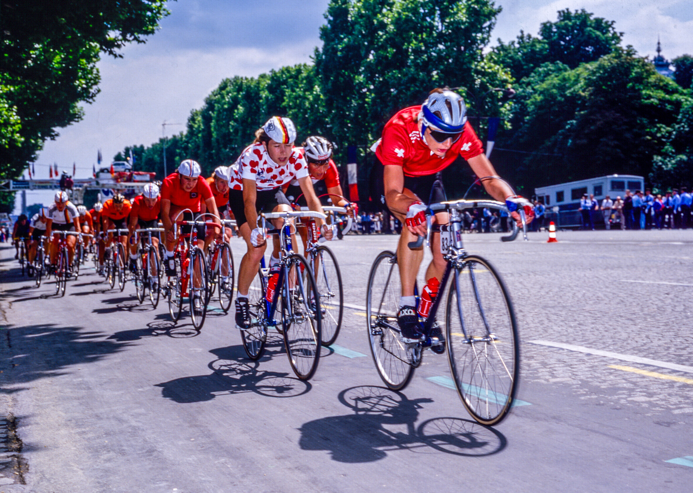 Female cyclists riding in a peloton during the Tour de France F&eacute;minin in the 1980s, with a rider in the polka dot jersey near the front.